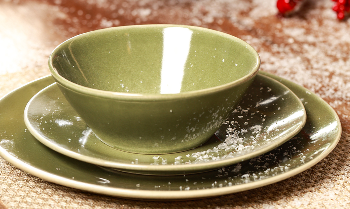 Green ceramic dinnerware set on festive table.